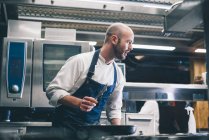Koch beugt sich über Herd in Restaurantküche — Stockfoto