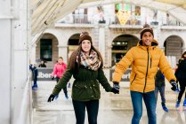 Fröhliches Paar hält Händchen auf Eisbahn — Stockfoto