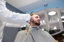 Man grooming customer beard with machine — Stock Photo