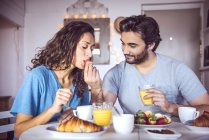 Young man feeding girlfriend at breakfast — Stock Photo