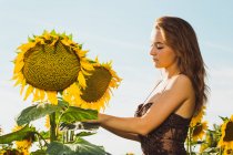 Junge Frau posiert mit Sonnenblumen über dem Himmel — Stockfoto