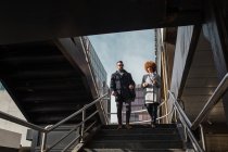 Fröhliches stylisches Paar geht Treppe hinunter — Stockfoto