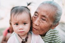 Нонг ХИО, ЛАОС: Старшая местная женщина обнимает прекрасную девушку с грустным лицом . — стоковое фото