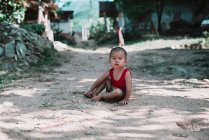 НОНГ ХЬЯУ, ЛАОС: Счастливый местный мальчик, сидящий на деревенской улице и смотрящий в камеру . — стоковое фото