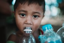 LAOS, 4000 ILHAS ÁREA: Menino água potável de garrafa de plástico e olhando para a câmera . — Fotografia de Stock