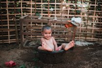 Nong khiaw, laos: lächelndes Kind, das in die Kamera schaut, während es im Waschbecken sitzt. — Stockfoto