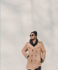 Stylish man in sunglasses and coat leaning on wall — Stock Photo