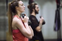 Mann und Frau trainieren mit Kurzhanteln im Fitnessstudio — Stockfoto