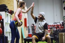 Alegre deportista hombre y mujer dando alta cinco mientras que el entrenamiento en el gimnasio . - foto de stock