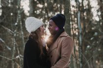 Backlit casal multirracial ligação na floresta de inverno — Fotografia de Stock