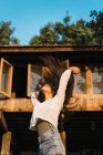 Junge brünette Frau wedelt mit Haaren vor dem Hintergrund des Hauses — Stockfoto