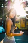 Alegre mujer asiática caminando en la calle en la luz del sol - foto de stock