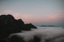 Clouds near mountain peaks at sunset dusk — Stock Photo