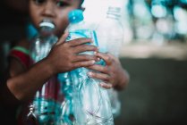 LAOS, 4000 ISLANDS AREA: Crop boy with plastic bottles — Stock Photo