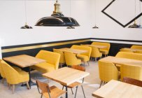 Empty wooden tables and yellow chairs in cafe — Stock Photo