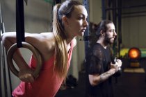 Vue latérale d'un homme et d'une femme sportifs faisant de l'exercice en salle de gym . — Photo de stock