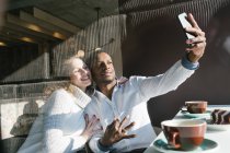 Couple souriant prenant selfie avec smartphone dans un café — Photo de stock