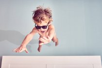 Fröhlicher kleiner Junge mit Sonnenbrille in der Luft — Stockfoto