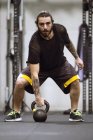 Спортивный человек, стоящий в спортзале и тренирующийся с гантелями . — стоковое фото