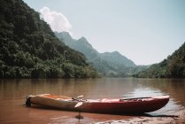 Canoa di legno in piedi sulla riva del fiume che attraversa le montagne — Foto stock