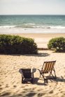 Два порожні шезлонги розміщені на сонячному піщаному пляжі в океані . — стокове фото