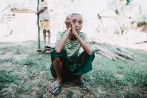 Nong khiaw, laos: reife einheimische Frau sitzt auf Gras und blickt in die Kamera — Stockfoto