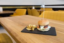 Burger and fries served on wooden table — Stock Photo