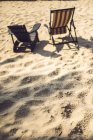 Duas espreguiçadeiras na praia de areia iluminada pelo sol — Fotografia de Stock