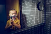Kleiner Junge rasiert sich am Badezimmerspiegel — Stockfoto