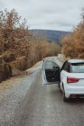 Car with opened driver 's door parked on rural autumn road — стоковое фото
