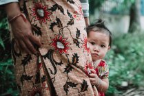 LAOS, 4000 ÎLES AREA : Petit enfant regardant la caméra tout en se cachant derrière la mère de la culture en jupe . — Photo de stock