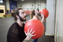 Sporty man and woman exercising with red balls in gym. — Stock Photo
