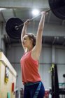 Jolie femme en forme soulevant haltère à la salle de gym — Photo de stock