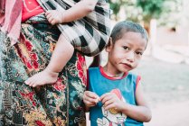 Nong Khiaw, Лаос: Хлопчик з брудним обличчям, стоячи на вулиці біля матері і дивлячись на камеру — стокове фото