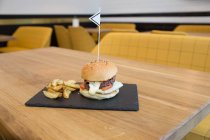 Burger and fries served square plate on wooden table — Stock Photo