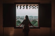 Back view woman looking in window to cityscape — Stock Photo