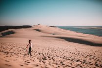 Вид збоку жінки, що стоїть на піску і насолоджується сонцем . — стокове фото