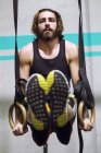 Fitter Mann hängt beim Training im Fitnessstudio an Ringen. — Stockfoto