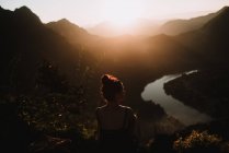 Зворотний силует жінки, що милується мальовничим заходом сонця в горах — стокове фото