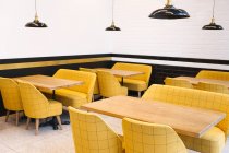 Tavoli di legno vuoti e sedie gialle nel caffè — Foto stock