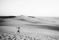 Distant view of woman cheerfully running on sand dunes — Stock Photo