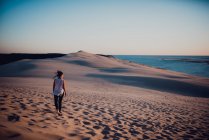 Задній вид жінка, ходьба по піску і дивиться в бік — стокове фото