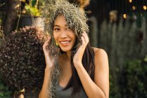 Fröhliche junge Frau blickt in die Kamera und posiert mit trockenem Gras auf den Haaren. — Stockfoto