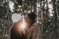 Sensuale coppia legame nella foresta invernale oltre fasci di tramonto — Foto stock