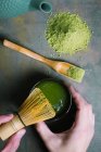 Manos de cultivo preparando té matcha con batidor de bambú - foto de stock
