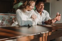 Веселая пара со смартфоном на свидании в кафе — стоковое фото