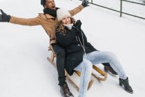 Happy couple riding sledge on snow — Stock Photo