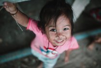 LAOS, 4000 ISLAS ÁREA: De arriba plano de niña en camiseta rosa sonriendo a la cámara . - foto de stock