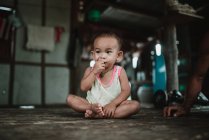 LAOS, 4000 ISLANDS AREA: Adorable toddler sitting on wooden floor and eating. — Stock Photo