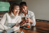 Bonding couple using smartphone in cafe — Stock Photo
